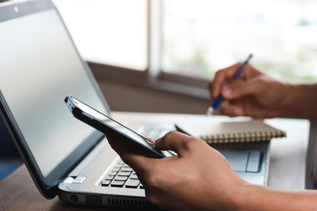 A person using a laptop and phone to get in touch